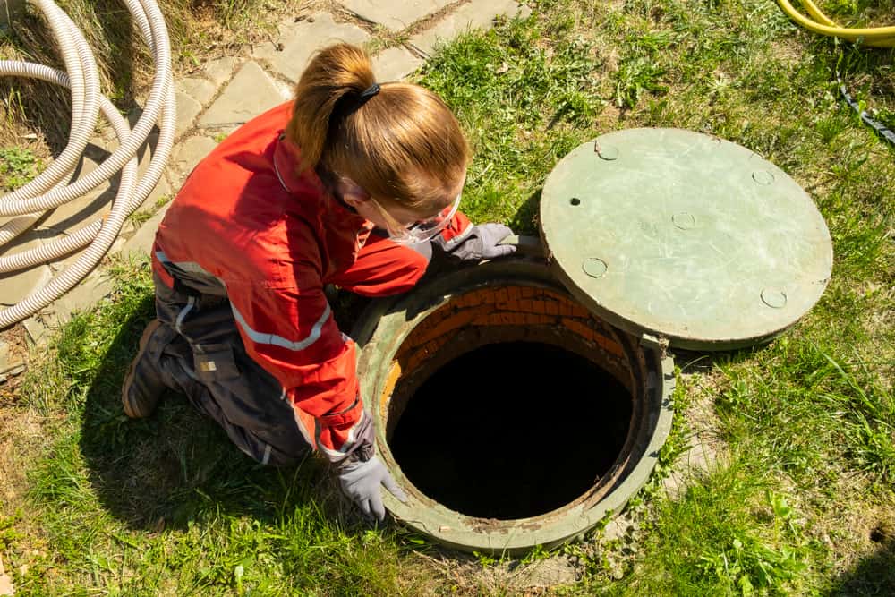 Girl,Plumber,Looks,Into,An,Open,Draining,Manhole.,Service,Of