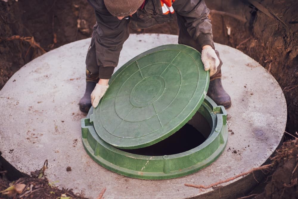 A,Worker,Lifts,The,Manhole,Cover,Of,A,Sewer,Well.
