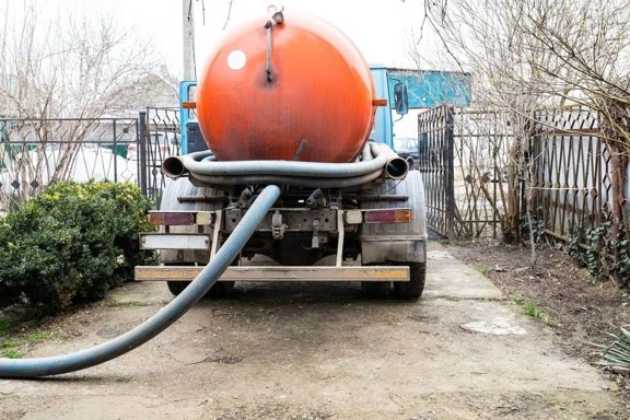 Septic pumping truck parked for residential cesspool service in a Long Island backyard